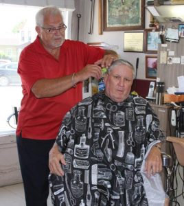 Longtime Dupo barber Dean Hudson combs back his friend Ralph Ochs’ hair. (Sean McGowan photo)