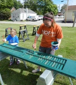 Hope Christian Church volunteers work on the Miller-Fiege Home across from Columbia City Hall during Impact Day. The Miller-Fiege Home is a certified landmark and is part of the city’s ongoing historic preservation efforts. Pictured, from left, Kendal and Courtney Frizzelle paint a window shutter for the home. (submitted photo)