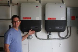 David Barmann of Valmeyer shows off the inverters for his solar installation. The inverters convert the direct current output of his solar panels into alternating current that powers the home’s electricity. (Sean McGowan photo)