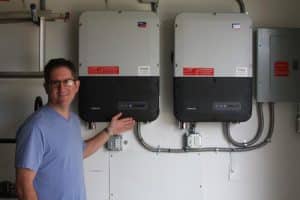 David Barmann of Valmeyer shows off the inverters for his solar installation. The inverters convert the direct current output of his solar panels into alternating current that powers the home’s electricity. (Sean McGowan photo)