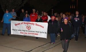 House of Neighborly Service volunteers and supporters march along with law enforcement personnel and others from the community during a Peace Walk held in Valmeyer on Thursday night. (Sean McGowan photo)