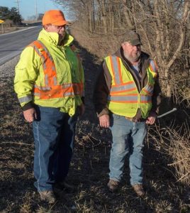Illinois Department of Transportation employees Dennis Hepp, left, and Joe Braun survey the site where they found Christopher Belfield trapped in a mangled SUV partially submerged in water. Pictured at right is Christopher Belfield’s Ford Expedition in which he was trapped for three days in a ravine outside Hecker. (Alan Dooley and submitted photo)