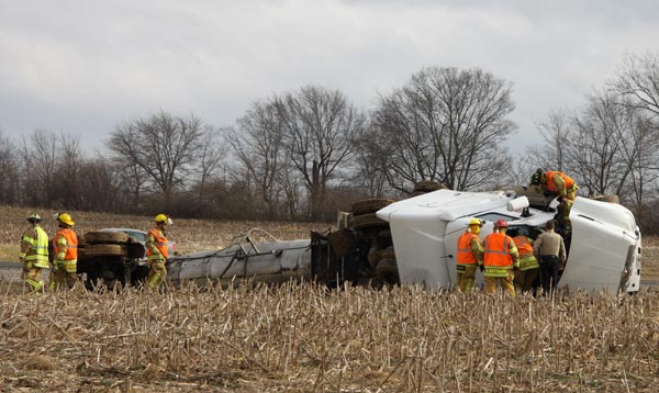 Emergency personnel work to free the driver of a tanker truck that rolled over on Route 3 near South Library Street.