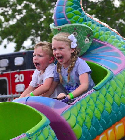 From left, Thomas Newcom, 3, and Skylar Newcom, 5, of Columbia enjoy the dragon ride during Carnival Armband Night at the Monroe County Fair on Thursday. For more photos from fair week, visit www.republictimes.net/photo-store. (John Spytek photo)