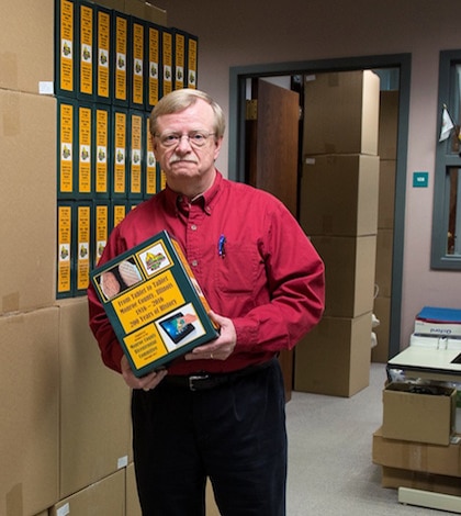 Monroe County Clerk Dennis Knobloch, author of the book set “From Tablet to Tablet, Monroe County, Illinois, 1816-2016, 200 Years of History,” holds one of the slip covers for his new book. Alongside him are 74 more boxes of the slip covers. (Alan Dooley photo)