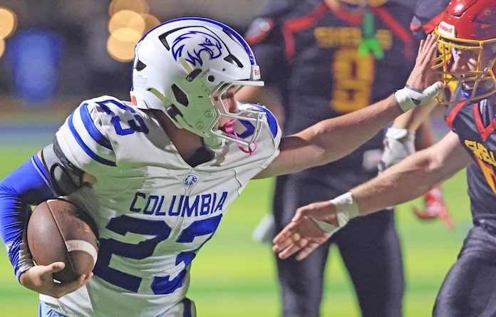 Cooper Weik (23) of Columbia stiff arms a Roxana player at Roxana High School on Friday September 19, 2025.